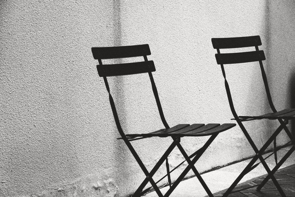 Dos sillas enfrentadas junto a una pared, en blanco y negro